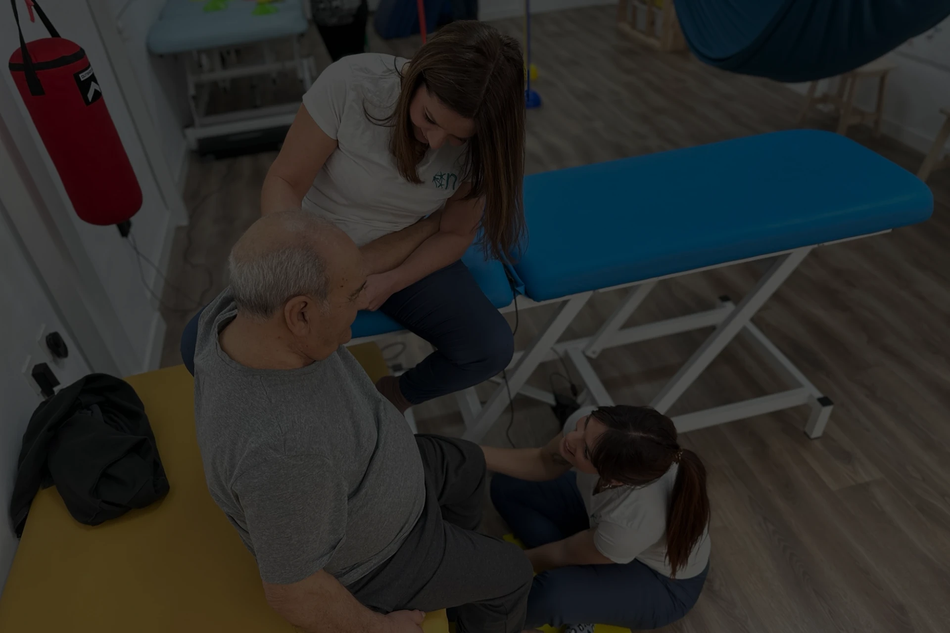 Imagen de dos profesionales de másNeuro Motril ayudando a realizar ejercicios de rehabilitación a un paciente de avanzada edad